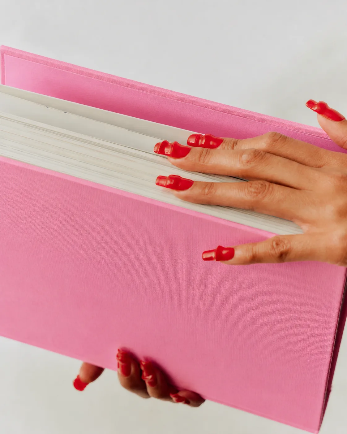 Hands opening a pink book